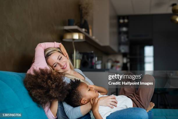 two little multiracial kids with mother sitting on sofa at home. - boy and girl talking fotografías e imágenes de stock