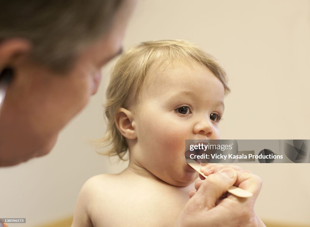 Toddler boy opening his mouth for doctor exam.