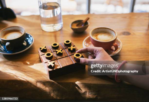 women playing board game at table in cafe. - tic tac toe stock pictures, royalty-free photos & images