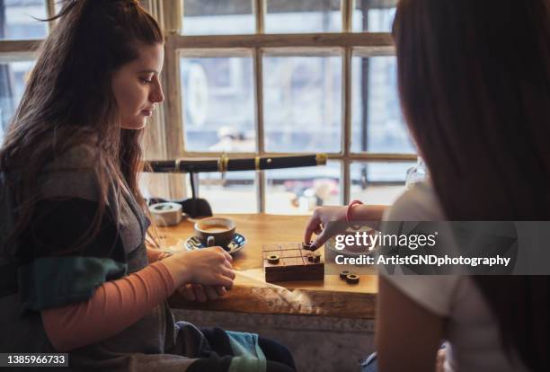 friends at a cafe playing tic tac toe. - table numbers stock pictures, royalty-free photos & images