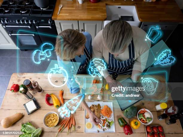 senior couple cooking at home and using technology to do a calorie count - food-ai stock pictures, royalty-free photos & images