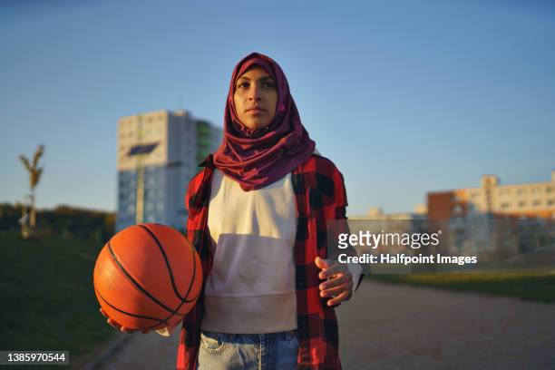 muslim young woman outdoors in the city, with basketball. - hijab fashion stockfoto's en -beelden