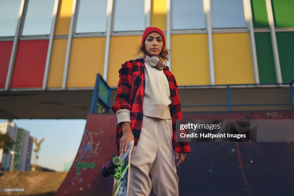 Young modern woman outdoors in the city, with skateboard.