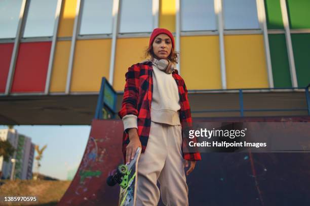 young modern woman outdoors in the city, with skateboard. - moda da rua imagens e fotografias de stock