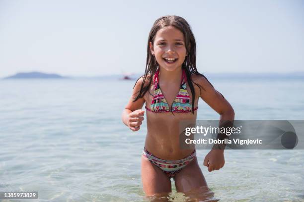 glückliches kleines mädchen, das im wasser steht und lacht - pretty girls in swimsuits stock-fotos und bilder