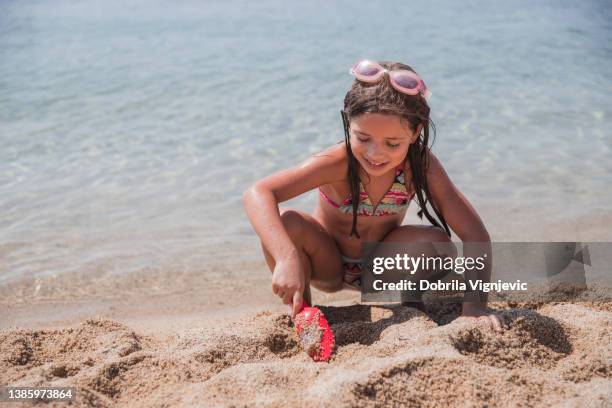 glückliches mädchen mit spatelspielzeug beim spielen am strand - pretty girls in swimsuits stock-fotos und bilder