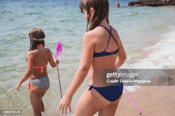 girl with swimming goggles standing on the beach and holding a fish net - tween girls swimwear 個照片及圖片檔