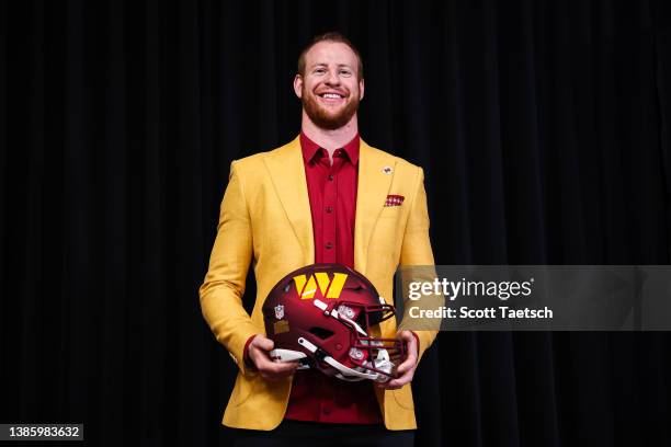 Quarterback Carson Wentz of the Washington Commanders stands with a helmet after being introduced at Inova Sports Performance Center on March 17,...