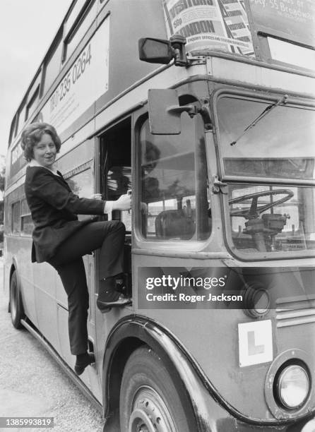 Rosamund Viner, London's first woman bus driver climbs aboard the drivers cab of the London Transport AEC Regent RT Class front-engined double-decker...