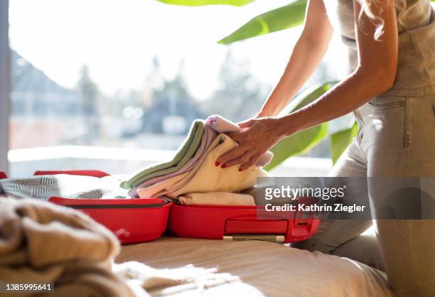 woman packing/unpacking suitcase on her bed - open suitcase stock pictures, royalty-free photos & images