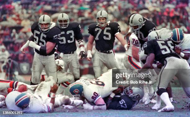 Raiders Howie Long , Rod Martin , Matt Millen and teammates stop Broncos running back for a loss during game action of Los Angeles Raiders vs Denver...