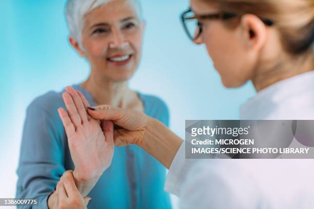 doctor doing carpal tunnel syndrome test with a senior woman - carpaletunnelsyndroom stockfoto's en -beelden