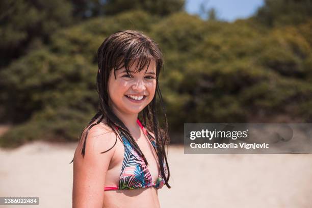 glückliches mädchen, das am strand steht und lächelt - pretty girls in swimsuits stock-fotos und bilder