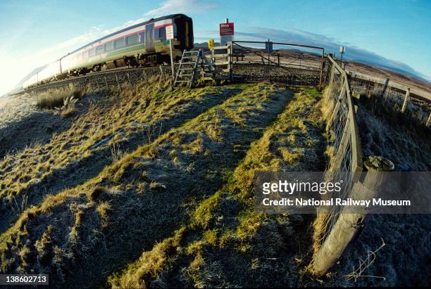Photographed in December 2002, a ScotRail service train travels north to Inverness approaching the level crossing at Cuaich. This is just one of the...
