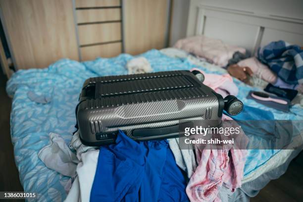 a chaotic scene of piles of clothes and luggage. - interim stock pictures, royalty-free photos & images