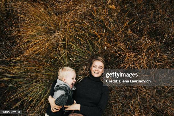 mom and son lie on the grass and laugh. view from above. happy mother's day. autumn photo - moments daily life from above photos et images de collection