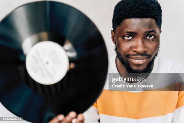 handsome african american man is holding a retro vinyl record looking at camera - awards concert photos et images de collection