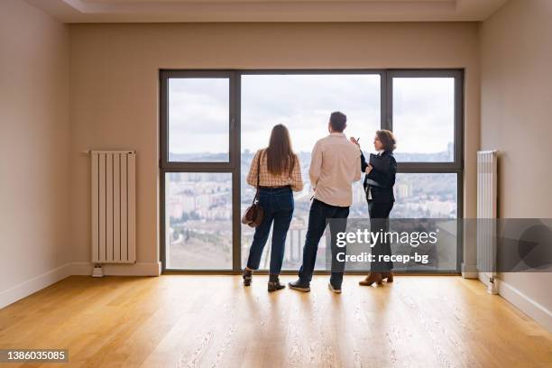 female real estate agent showing house to young couple - condominio imagens e fotografias de stock