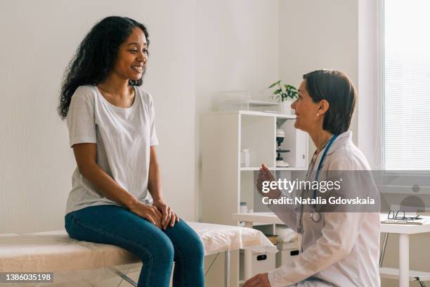 cheerful african-american patient visiting mature doctor and sharing disease symptoms - patient history stock pictures, royalty-free photos & images