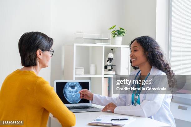 afro-american healthcare worker discussing medical x-ray scan with mature female patient - screening of ill see you in my dreams arrivals stockfoto's en -beelden