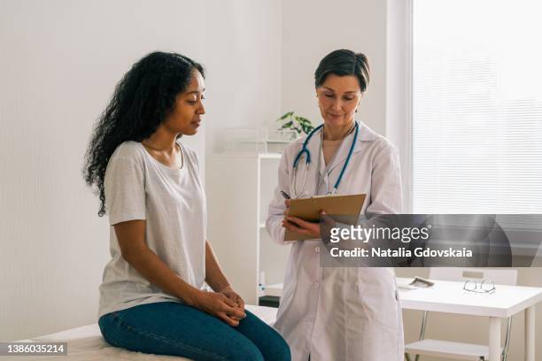 african-american female patient visiting doctor office telling about symptoms. medical consultation - treatment room stock pictures, royalty-free photos & images