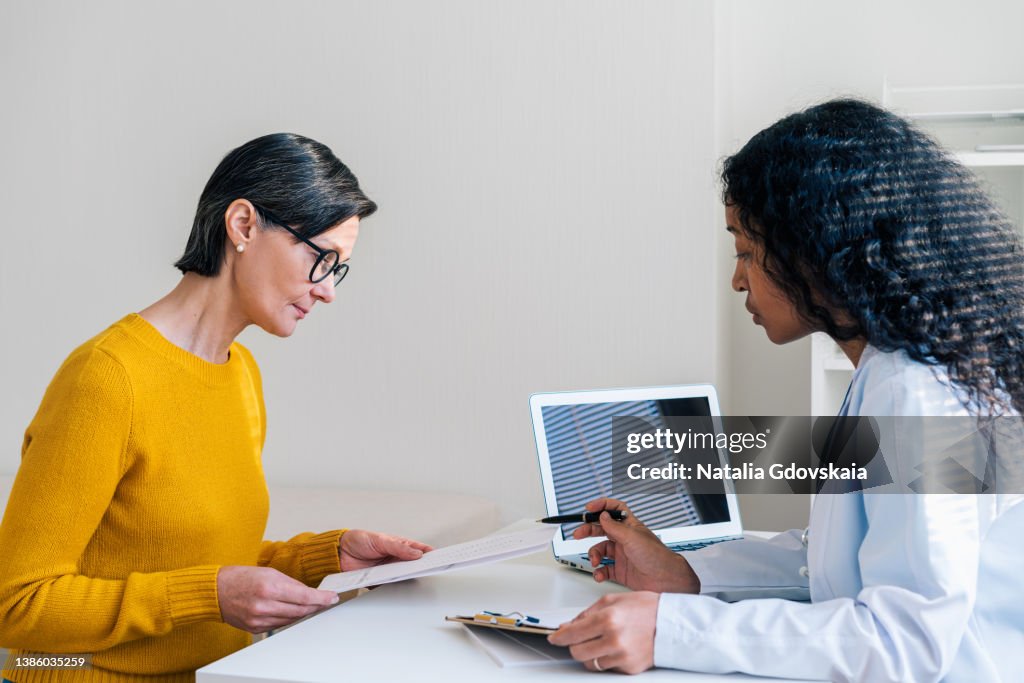 African-American doctor consulting female patient, giving instructions and recommendations