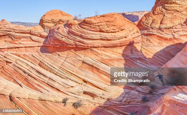 hiker exploring the famous wave of coyote buttes north in the paria canyon-vermilion cliffs wilderness of the colorado plateau in southern utah and northern arizona usa - southern utah v utah stock pictures, royalty-free photos & images