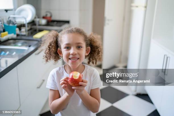 petite fille mangeant des fruits dans la cuisine à la maison - kids play apple photos et images de collection