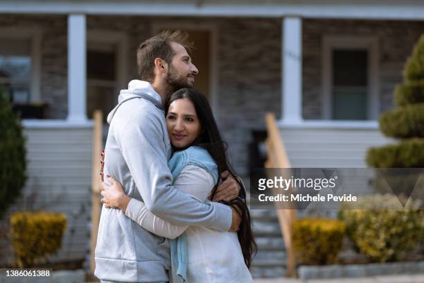 adult brother and sister hugging in front of their house - brother hug stock pictures, royalty-free photos & images