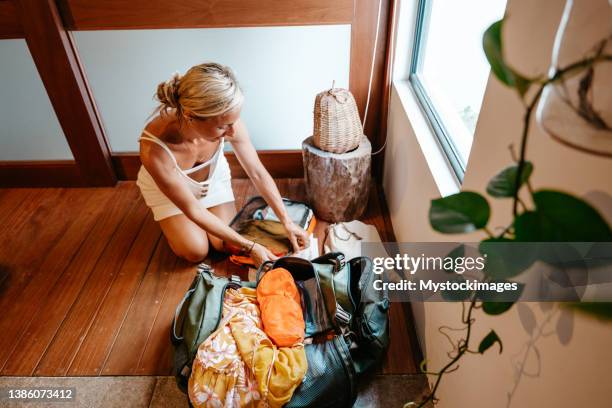 young woman packing clothes in a backpack ready to leave for a trip - duffel tas stockfoto's en -beelden