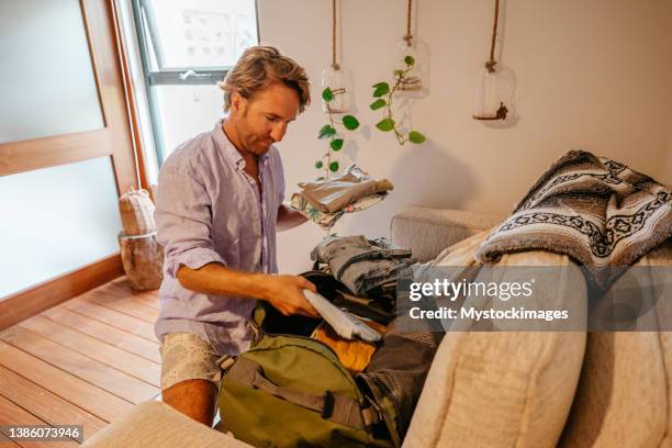 male traveler packing for a trip, puts clothes in a duffel bag - duffel tas stockfoto's en -beelden