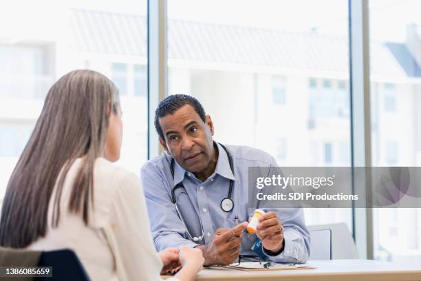 male general practitioner explains drug side effects to unrecognizable patient - showing empathy stock pictures, royalty-free photos & images