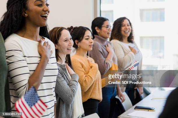 diverse group puts hand over heart to recite pledge - american flag on stand stock pictures, royalty-free photos & images