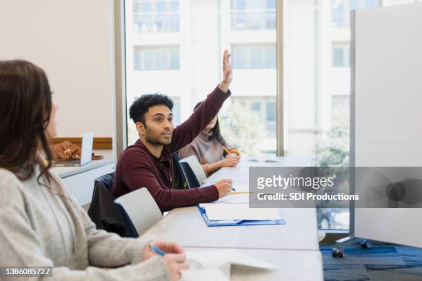 young man eagerly raises hand in class - indian college students imagens e fotografias de stock