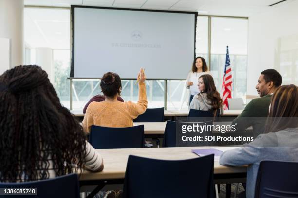 vue arrière femme levant la main dans la classe de citoyenneté américaine - projector classroom photos et images de collection