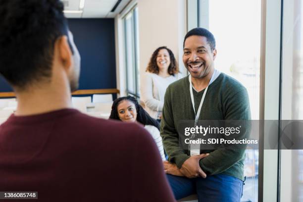 mature professor smiles and jokes with unrecognizable male student - citizenship stockfoto's en -beelden