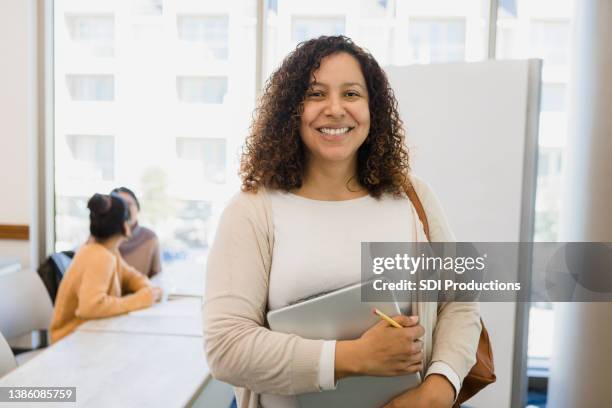 non-traditional female college student holding laptop smiles for camera - non traditional learning stock pictures, royalty-free photos & images