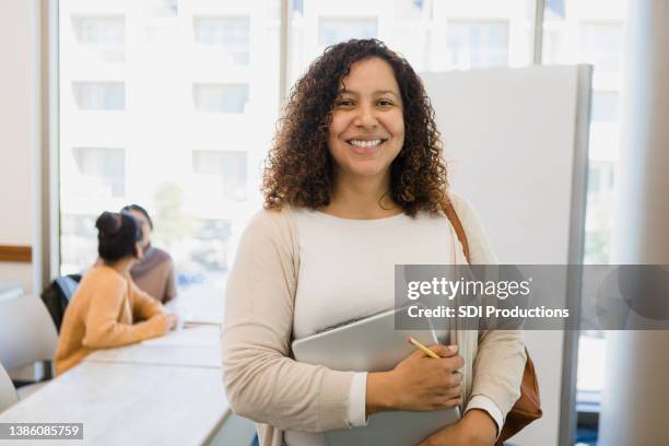 non-traditional female college student holding laptop smiles for camera - adult learning stock pictures, royalty-free photos & images