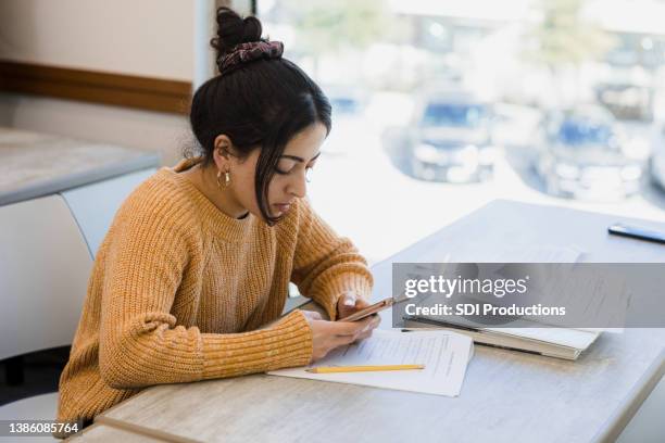 young woman uses phone to find answers for test - college application stockfoto's en -beelden