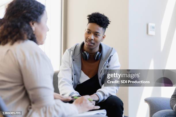 counselor talks to young man and unseen sister - male medical professional stock pictures, royalty-free photos & images