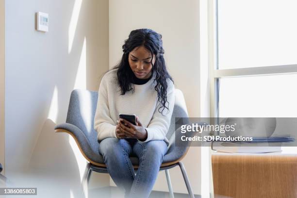mujer adulta joven estresada mira las redes sociales por teléfono - black girls fotografías e imágenes de stock