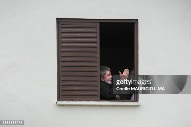 Brazil's President Luiz Inacio Lula da Silva peers from a new apartment's window during a ceremony to deliver 224 new houses as part of his...