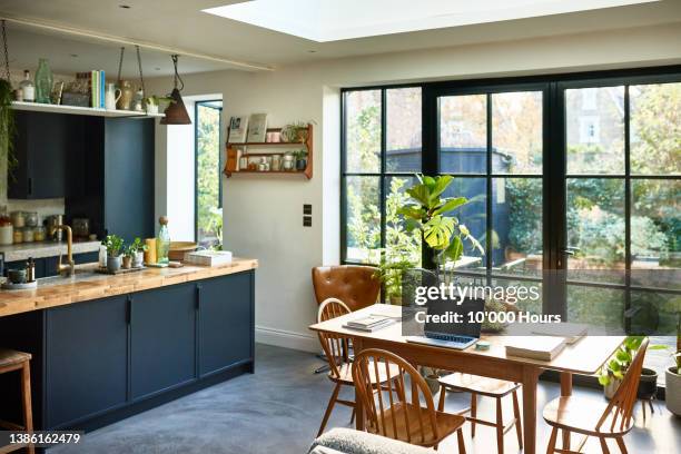 empty modern kitchen with laptop on table and patio doors into garden - porte d'accès à la terrasse photos et images de collection