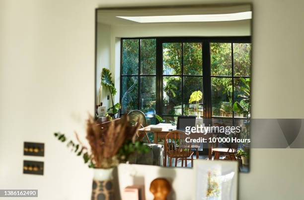 dining room and patio doors reflected in large mirror on wall - window with view on garden stockfoto's en -beelden