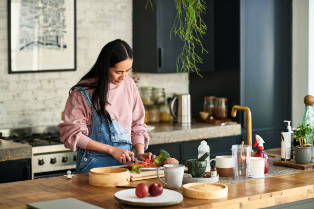 chinese woman prepares vegetable on kitchen worktop - cuisine preparation photos et images de collection