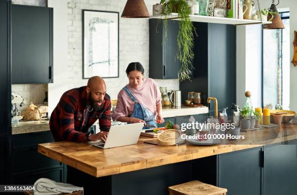 multiracial couple following online recipe on laptop in kitchen - following recipe stock pictures, royalty-free photos & images