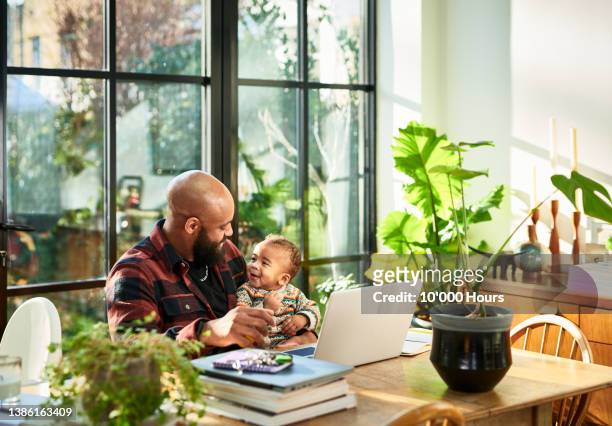 black father smiling face to face with baby son in front of laptop in home office - black baby 個照片及圖片檔