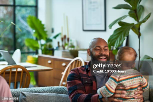 cheerful black father in his 30s bonding with baby son at home and smiling - s thirtysomething stock pictures, royalty-free photos & images