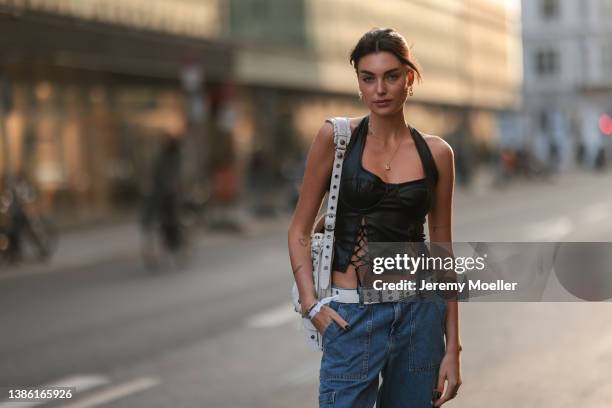 Celine Bethmann wearing gold jewelry, a black crop leather top, a Balenciaga white Le Cagole big leather bag, a white belt, blue jeans on March 16,...