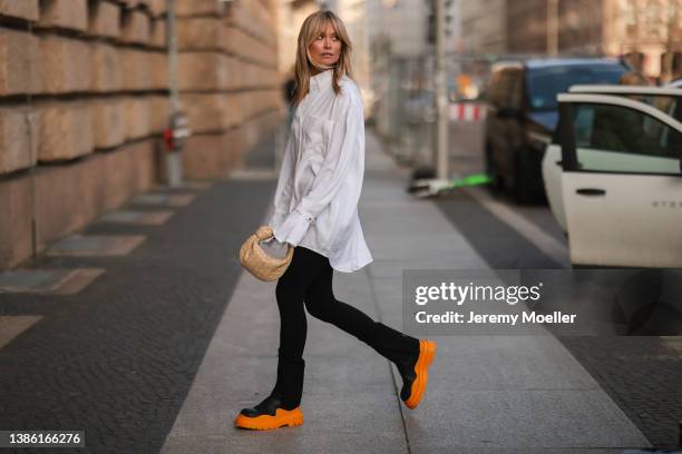 Nadine Berneis wearing a white oversize blouse, black pants, a Bottega Veneta mini beige Jodie leather bag and Bottega Veneta black and orange...